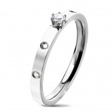 A steel ring in silver colour – a round zircon in claw setting, clear zircons, 3 mm